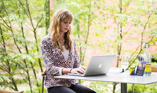 A student on her laptop surrounded by trees