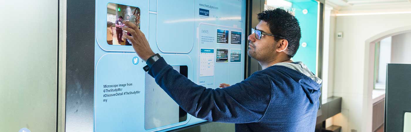 A student working on a project via a large touchscreen