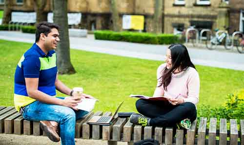 Two students sitting outside in the main University of Manchester campus